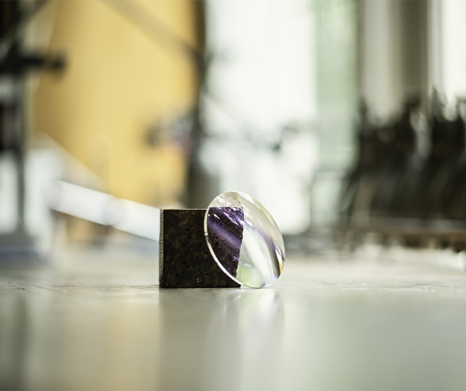 Brillenglas von Hoya liegt angelehnt an einem Stück Granit