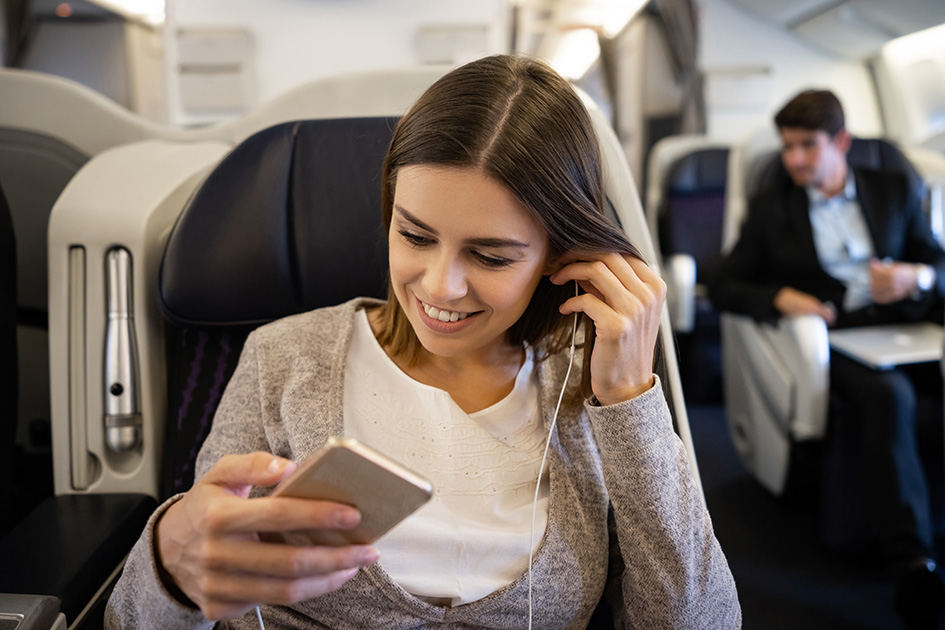 Junge Frau hört im Zug mit In-Ear-Monitoring Musik auf dem Weg zur Arbeit