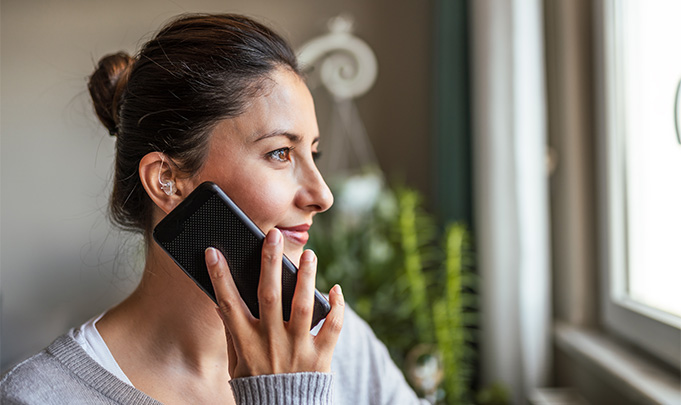 Junge Frau mit Hörgerät telefoniert über ihr Smartphone