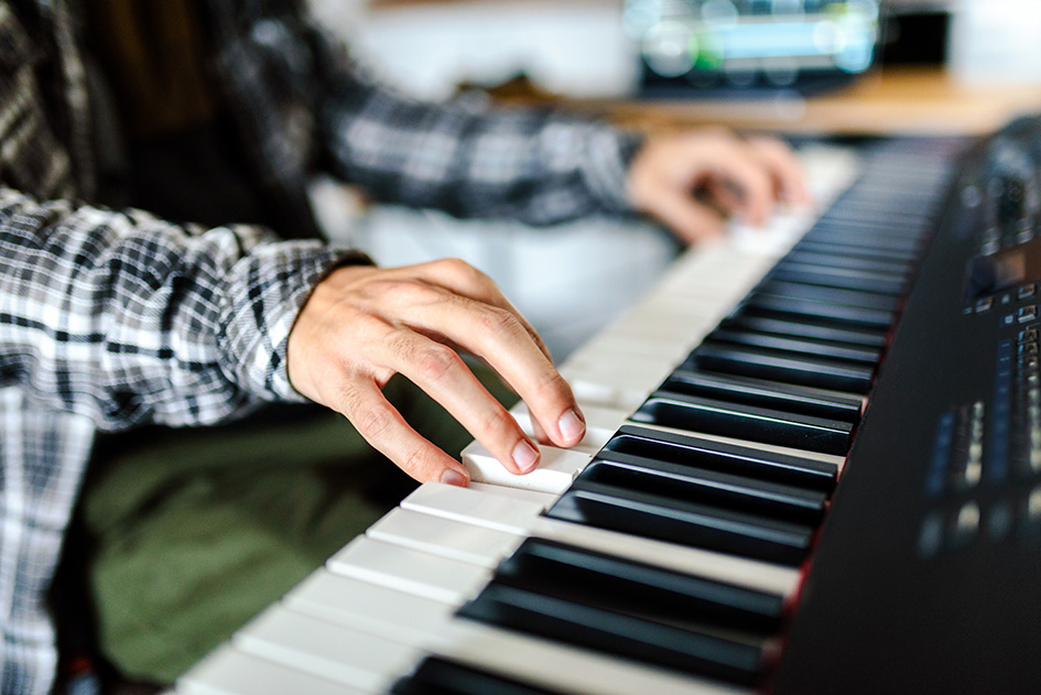 Nahaufnahme von Händen, die an einem Keyboard spielen