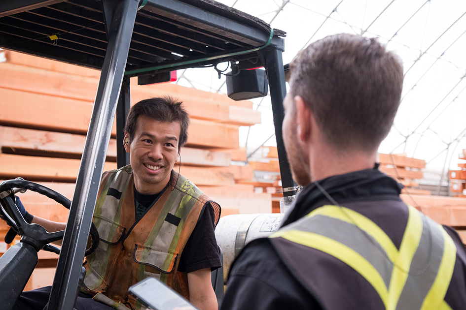 Gabelstapelfahrer und Lagermitarbeiter unterhalten sich mit Gehörschutz