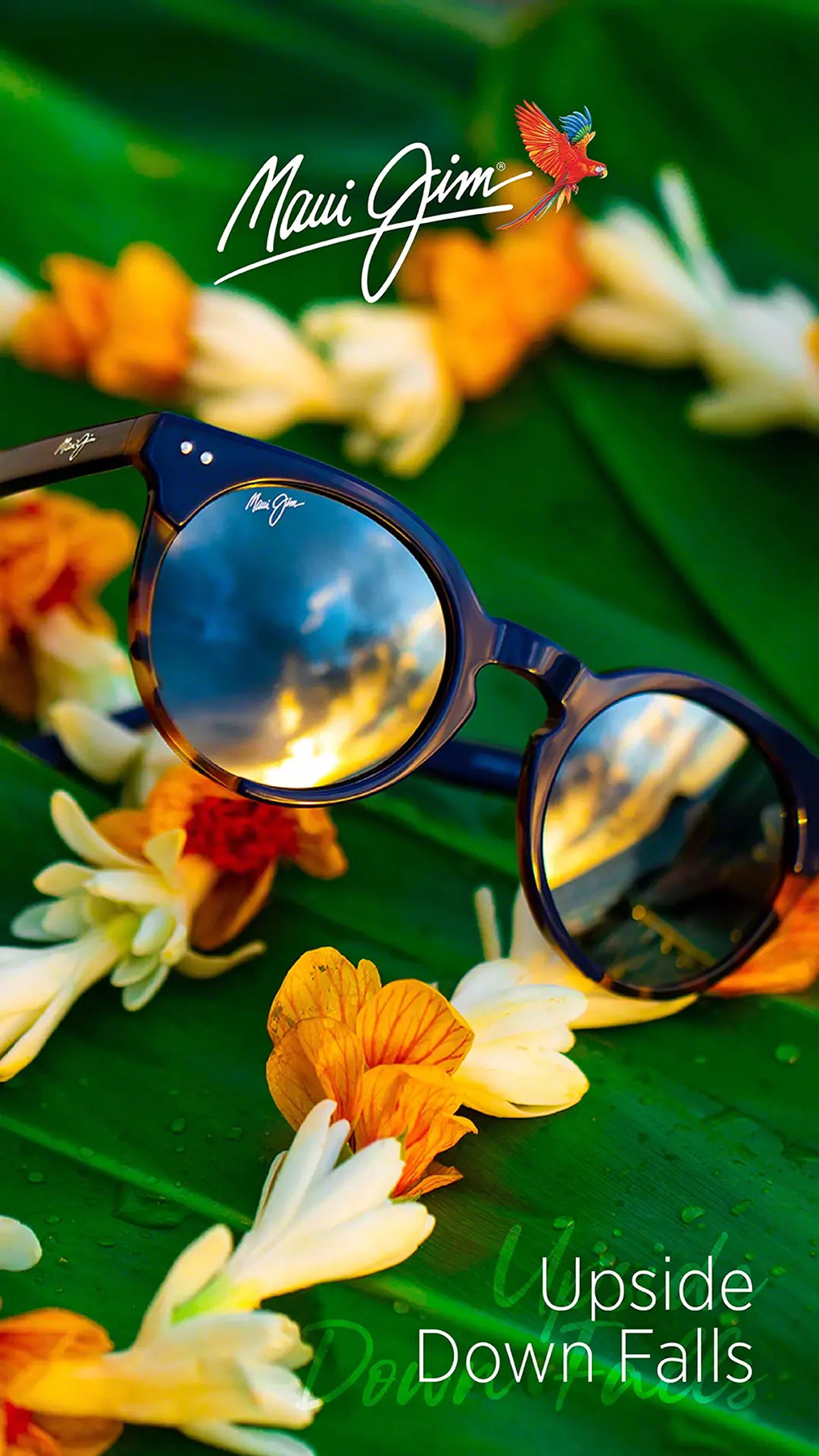 Runde Sonnebrille mit blauen polarisierenden Gläsern liegt auf einer Blumenkette und Palmenblättern