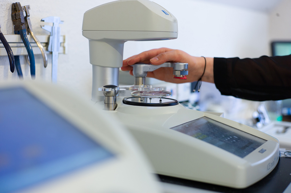 Hand bedient ein Gerät zur Brillenglasbearbeitung in der Werkstatt